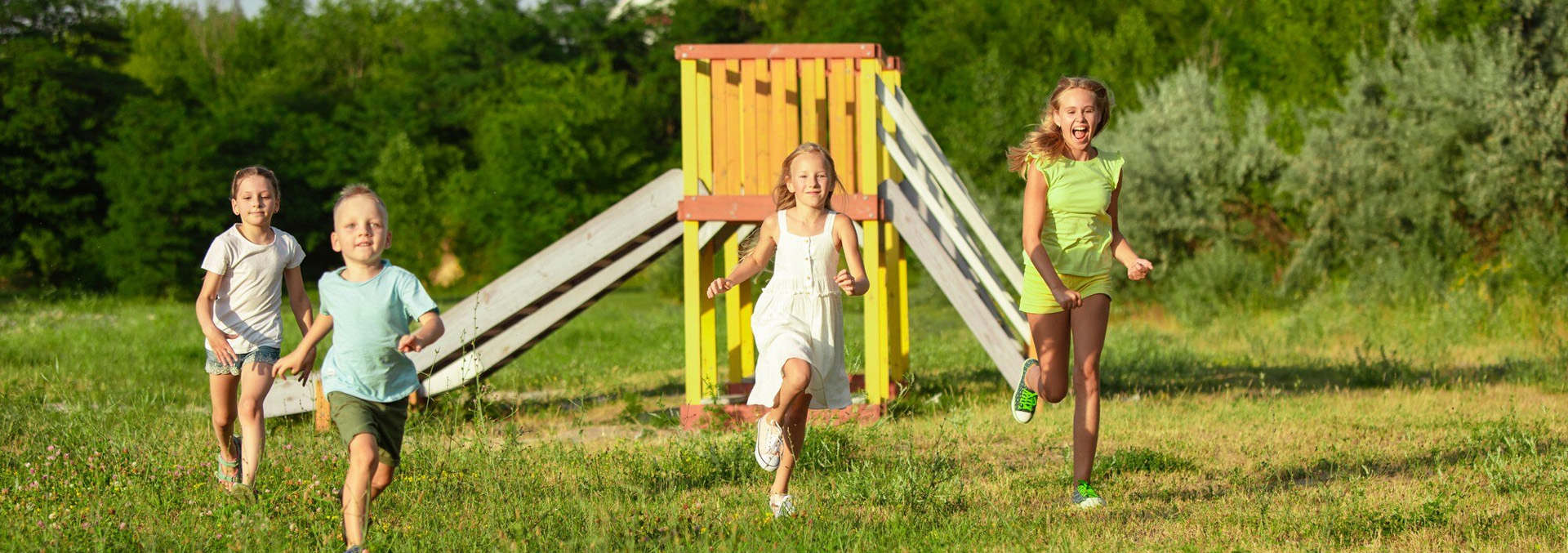 A simple wooden playground surrounded by a big open field and sunny blue skies at Texas Lakes Ranch RV Park in Aubrey, TX.
