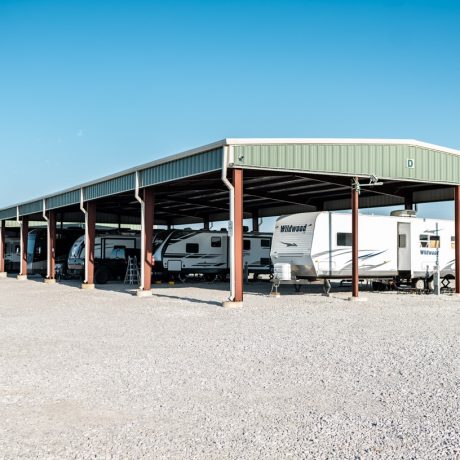 A row of RVs parked at full hookup sites, surrounded by the park’s natural beauty, illustrating the inviting atmosphere for extended stays at Texas Lakes Ranch RV Park in Aubrey, TX