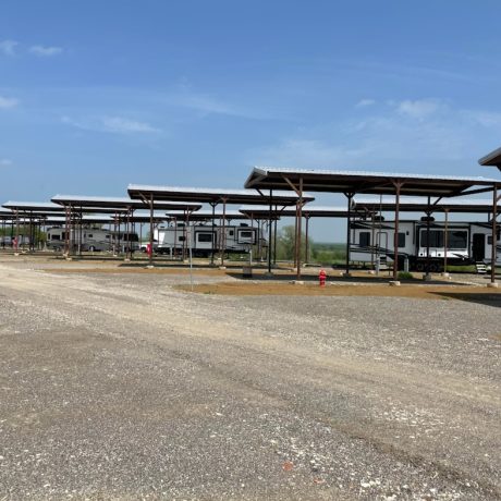 An RV parked in a full hookup site surrounded by green open space and outdoor scenery at Texas Lakes Ranch RV Park in Aubrey, TX.